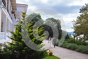 The bride and groom are quickly walking along the green park6 conducting an enthusiastic conversation, discussing the