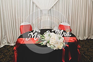 Bride and groom reception table is decorated with a white bouquet and champagne glasses