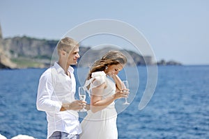 Bride and groom relaxing with champagne glass in wedding day near sea