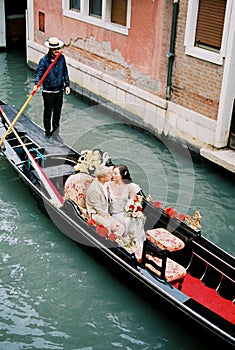 Bride and groom ride a gondola down a canal in Venice