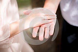 bride and groom with rings on their ring fingers hold their hands together. Summer wedding ceremony outdoors