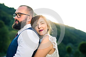 Bride and groom in romantic hug at sunset