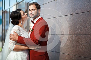 Bride and groom, romantic wedding couple in a passionate outburst, near walls of building.