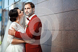 Bride and groom, romantic wedding couple in a passionate outburst, near walls of building. photo