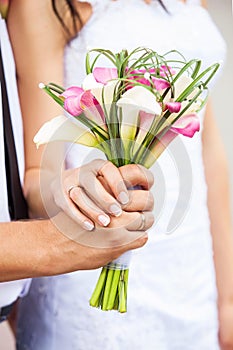 Bride and groom's hands with bouquet of callas