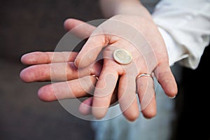 Bride and Groom& x27;s Hands Together Holding a Coin with Heart Symbol Close-Up