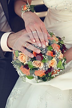 Bride and groom's hands with wedding rings and bouquet