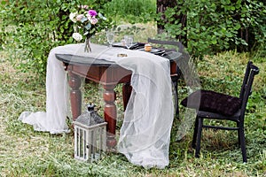 Bride and Groom's Wedding Table Set in a Lush Garden, adorned with Floral Decor, Rustic Details, and Elegant Cutlery