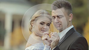Bride and groom show their wedding rings, kiss and