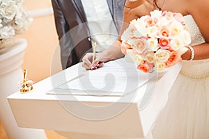 Bride and groom signing marriage wedding certificate at registry.