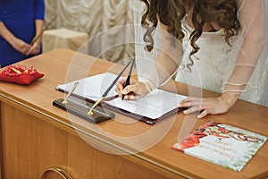 Bride and groom signing marriage wedding certificate at registry.