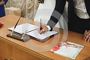 Bride and groom signing marriage wedding certificate at registry.