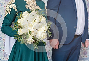 The bride and groom sit on chairs with their hands folded in prayer. Nikah is a Muslim wedding cerem