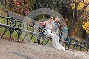 Bride and groom sitting on bench in a park