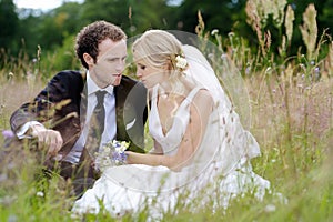 Bride and groom sitting in a meadow