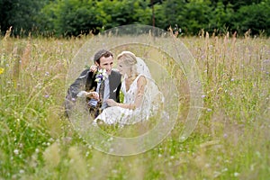 Bride and groom sitting in a meadow