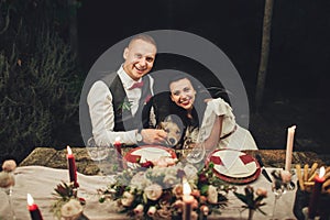 Bride and groom sitting at wedding table and smiling at camera