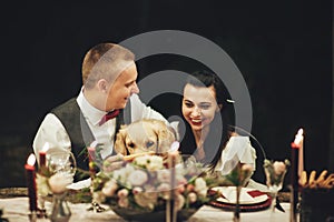 Bride and groom sitting at wedding table and smiling at camera