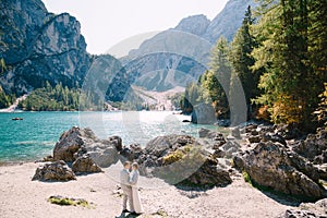 Bride and groom stand against the backdrop of stones overlooking Lago di Braies in Italy. Destination wedding in Europe