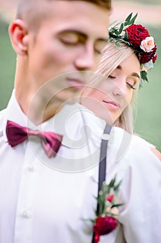 Bride and groom stand behind each other with closed eyes