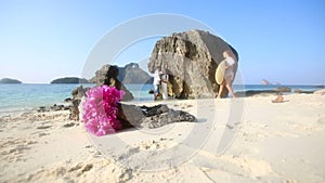 bride and groom stand by cliff with bouquet at foreground