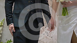 Bride and groom stand at the indoors wedding ceremony. Couple in love hold hands