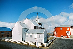 Bride and groom stand near a small wooden church. Iceland