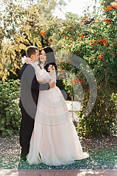 bride and groom stand by a rowan bush in the park.