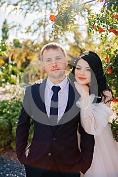 bride and groom stand by a rowan bush in the park.