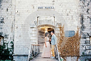 Bride and groom stand together on the bridge to Mamula Fort. Montenegro