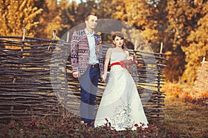 Bride and groom standing near the wicker fence holding hands