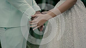 the bride and groom standing opposite each other in an open area join hands.