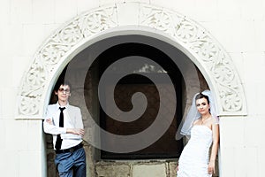 Bride and groom standing under white arch