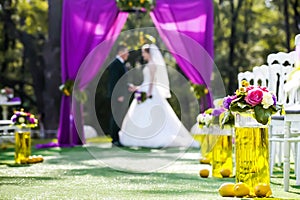 Bride and groom standing in wedding archway with chairs on on each side