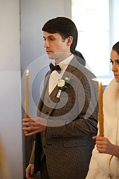 Bride and groom standing at wedding ceremony. Happy stylish wedding couple holding candles with light under golden