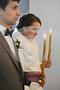 Bride and groom standing at wedding ceremony. Happy stylish wedding couple holding candles with light under golden