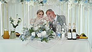 The bride and groom at the table at the banquet of their wedding.