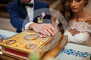 Bride and groom taking vows in church on old golden bible