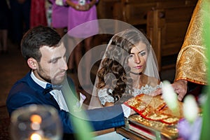 Bride and groom taking vows in church on old golden bible