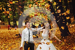 Bride and groom thow the yellow leaves up in the air