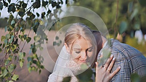 Bride and groom touching and enjoying each other against a backdrop of birch tree branches.