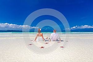 Bride and Groom on tropical beach shore with red starfis