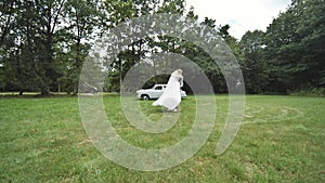 Bride and groom twirling in the background of a retro automobile.