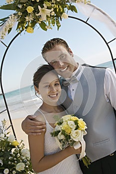 Bride and Groom under archway on beach