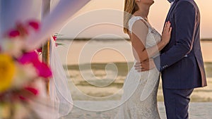 The bride and groom under archway on beach. Calm and romantic white sandy beach for honeymoon destination and love background