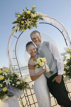 Bride and Groom under archway on beach (portrait)