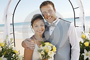 Bride and Groom under archway on beach (portrait)