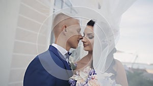 Bride and groom under a wedding veil. Loving couple have a tenderly time together. Man and woman kiss in wedding day.