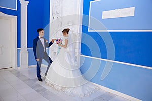 The bride and groom are waiting for the beginning of their marriage. A man in a blue suit carefully holds his beloved by