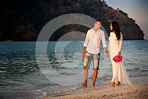 Bride and groom walk at beach at dawn